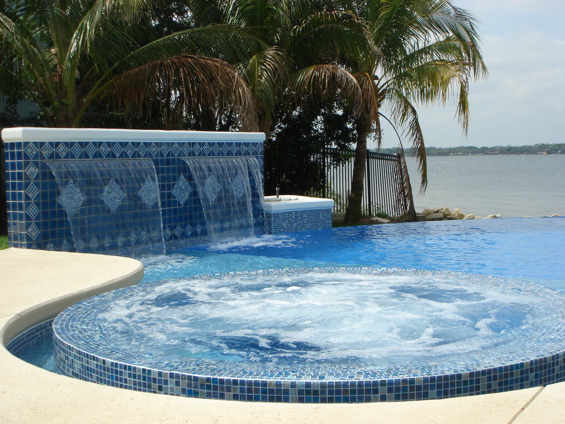 Blue mosaic wall pouring three sheer descent waterfalls into an infinity pool